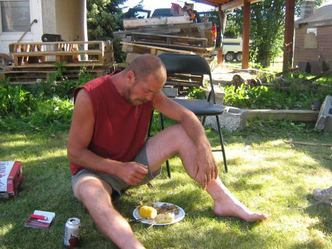 1995 Ford Bronco - A man enjoys a meal outdoors on a sunny day, with a plate of food and a beverage nearby.