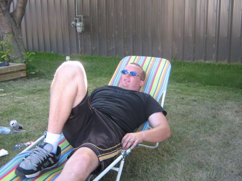 1995 Ford Bronco - A man relaxes on a lounge chair in a grassy backyard with a fence behind him.