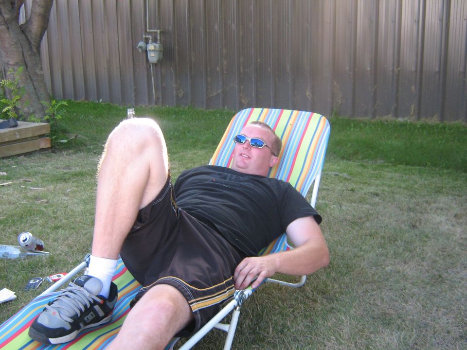 guy in sunglasses chilling on a striped lounge chair in a backyard