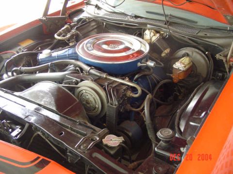 1973 Ford Ranchero - The engine bay of an orange vehicle shows the V8 engine and various components.