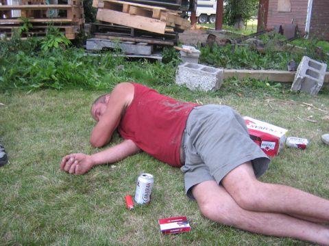 1995 Ford Bronco - A man is passed out on the lawn with beer and cigarettes nearby.