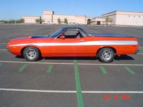 1973 Ford Ranchero - Side profile of a 1973 Ford Ranchero in orange with a silver stripe and black vinyl top, parked in a lot.