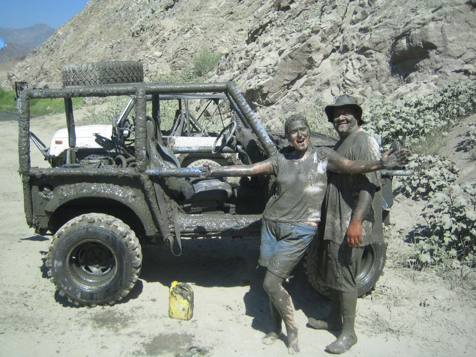 Mud-covered off-road vehicle with roll cage and two people