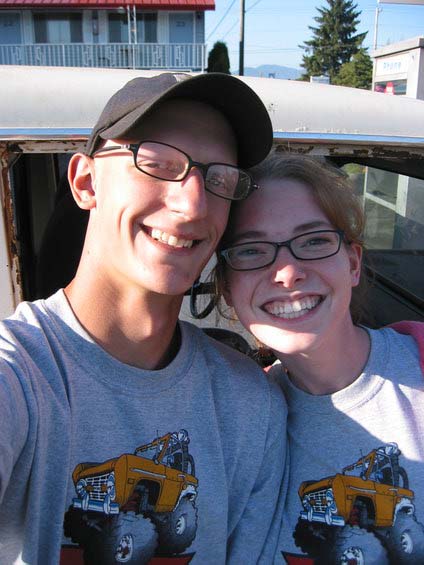 1991 Ford Explorer - A man and woman smile for a selfie in front of a weathered vehicle, both wearing graphic t-shirts.