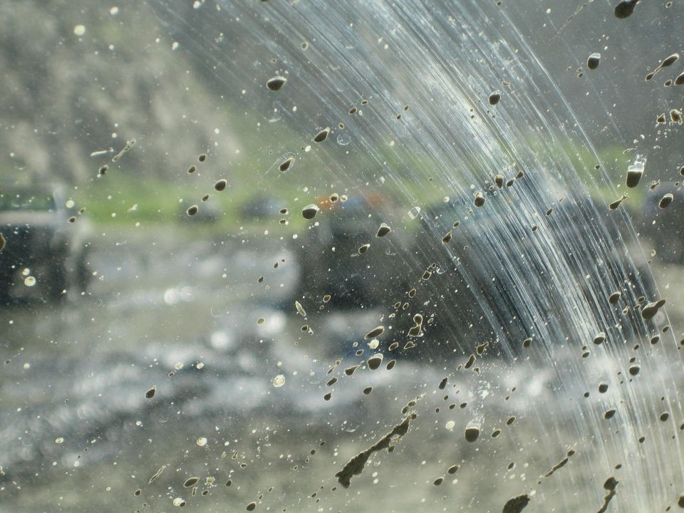mud splatters on windshield, blurry vehicle in background