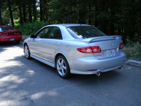 2004 Mazda 6 - Rear view of a silver 2004 Mazda 6 sedan with a spoiler and dual exhaust pipes, parked outdoors.