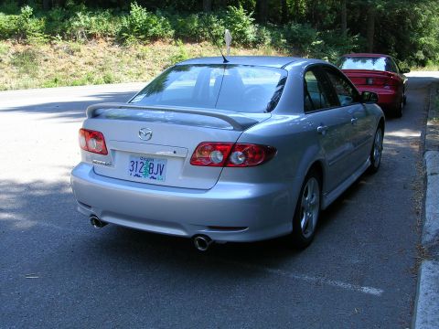 2004 Mazda 6 - The rear view of a silver Mazda 6 sedan, showing its taillights, spoiler, and dual exhaust pipes.