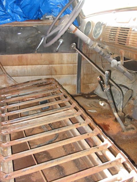 1951 Chevrolet C/K Pickup - The interior of this truck shows significant rust and wear, with a blue tarp covering part of the dashboard.