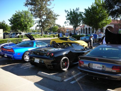 1998 Ford Crown Victoria - black Ferrari convertible parked between a blue Acura NSX and a gray sedan at a sunny outdoor car meet.
