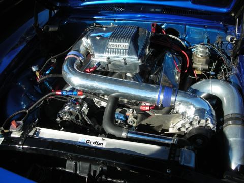 1998 Ford Crown Victoria - highly polished Vortech-supercharged engine with bright intercooler piping and a Griffin radiator fills a blue car's bay.