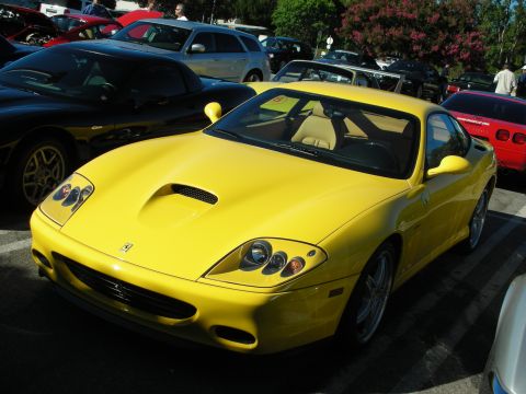 1998 Ford Crown Victoria - bright yellow Ferrari GT coupe with a tan interior and hood scoop parked among other cars at an outdoor show.
