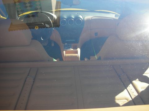 1998 Ford Crown Victoria - Sunlit view through a dusty windshield into a sports car cabin showing the dashboard, center console and seats.