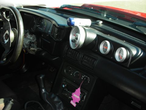 1998 Ford Crown Victoria - black car interior with steering wheel, aftermarket pillar and dash-mounted gauges, manual shifter and a pink air freshener.