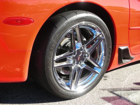 1998 Ford Crown Victoria - Close-up of a polished five-spoke wheel with drilled rotor and sticky tire on an orange sports car.