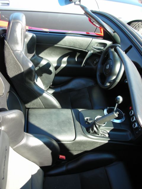 1998 Ford Crown Victoria - Interior of a black two-seat roadster showing suede-trimmed seats, gauges and a gated manual shifter.