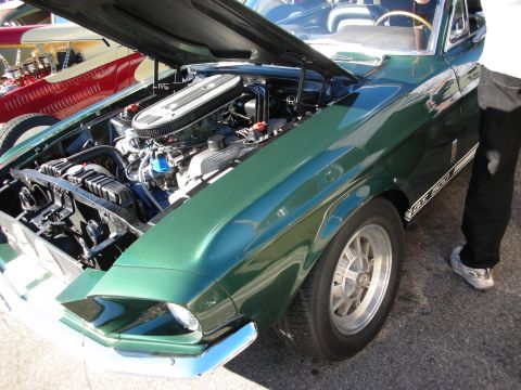 1998 Ford Crown Victoria - green Shelby GT500 Mustang fastback with chrome air cleaner and open hood parked at an outdoor show.