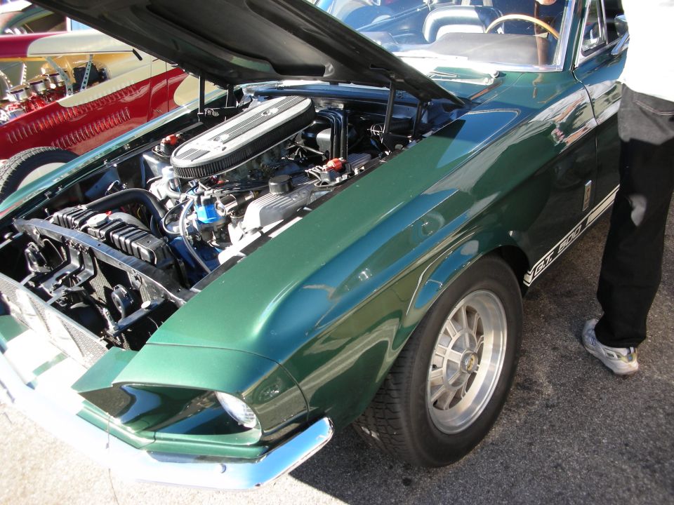 Green Shelby GT500 Mustang fastback with open hood at a car show