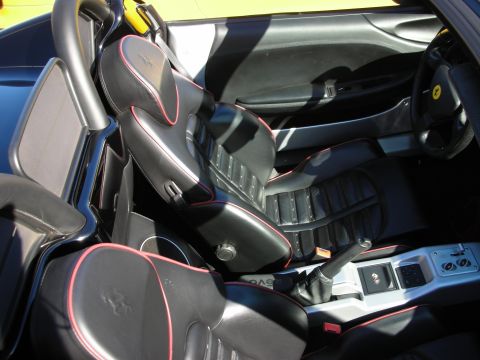 1998 Ford Crown Victoria - Black leather cockpit of a sports car with red-piped seats, a chrome gated manual shifter, and a yellow Ferrari emblem on the dash.