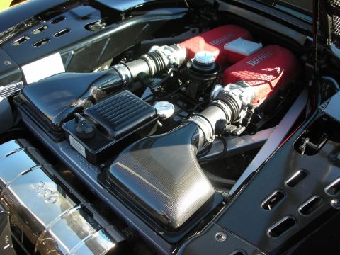 1998 Ford Crown Victoria - Engine bay of a Ferrari showing a red-finned V8 with chrome intake plumbing and a carbon-fiber airbox.