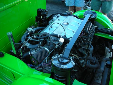 1998 Ford Crown Victoria - modern V8 engine fitted into a bright green hot rod, with a cone air filter and polished firewall bracing.