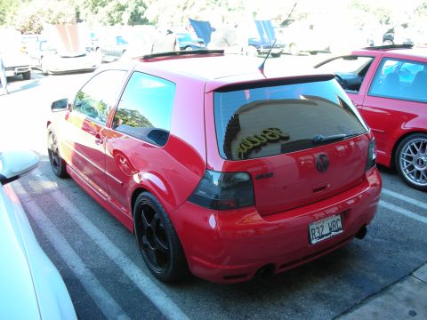 1998 Ford Crown Victoria - red Volkswagen R32 hatchback with black wheels and tinted glass, shown rear three-quarter in a parking lot.