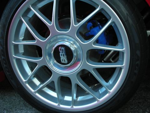 1998 Ford Crown Victoria - Close-up of a silver BBS multi-spoke alloy wheel with a blue brake caliper, mounted on a red car.