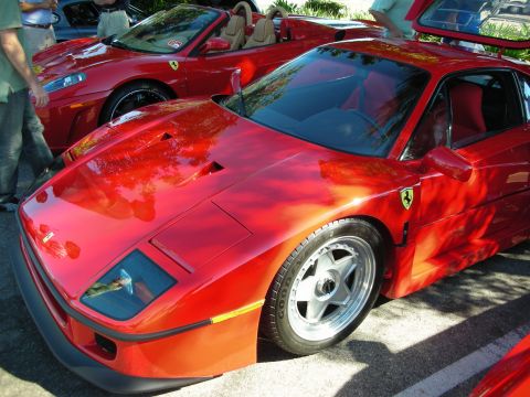 1998 Ford Crown Victoria - red Ferrari F40 with pop-up headlights and Prancing Horse badge, parked beside a red Ferrari convertible at a car show.