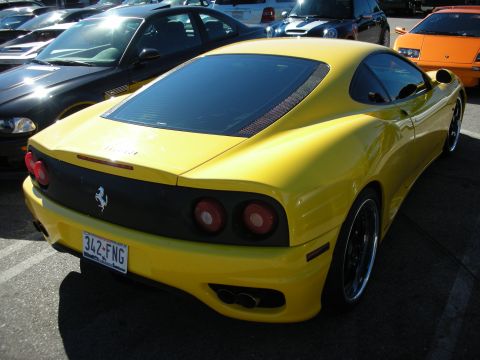 1998 Ford Crown Victoria - Rear of a yellow Ferrari 360 Modena with round taillights and Prancing Horse badge, plate '342 FNG', in a show lot.