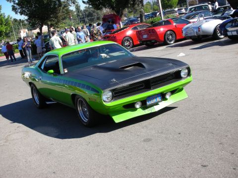 1998 Ford Crown Victoria - Lime-green Plymouth Barracuda muscle car with a matte-black hood and shaker scoop, parked among classics at a sunny car show.