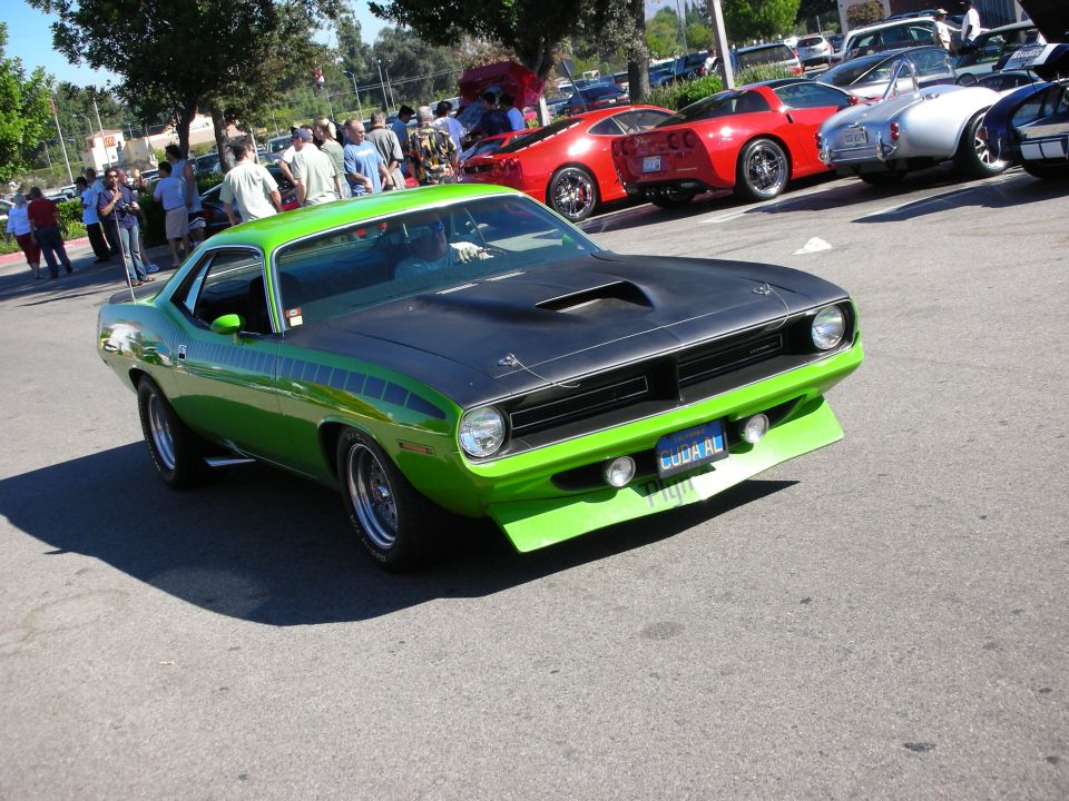 Green Plymouth Barracuda with matte-black hood and shaker scoop at a car show