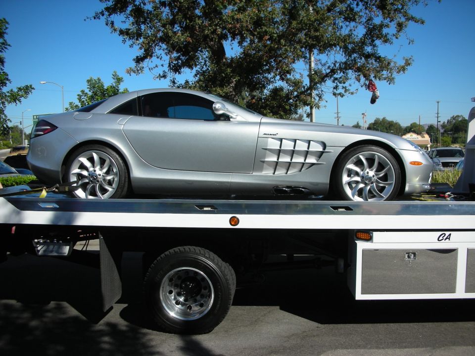 Silver Mercedes-Benz SLR McLaren on a flatbed truck showing side exhaust vents and McLaren badge