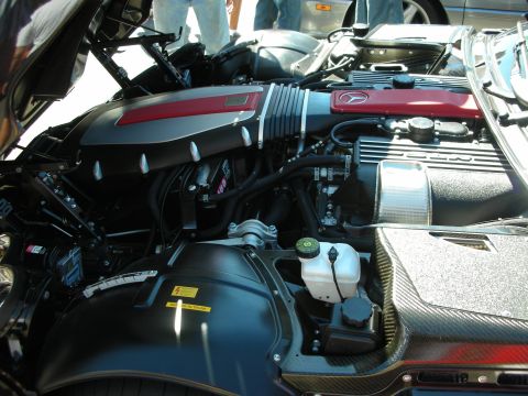 1998 Ford Crown Victoria - Open engine bay of a Dodge Viper showing the red Viper-stamped valve cover, carbon-fiber trim, intake and brake fluid reservoir.