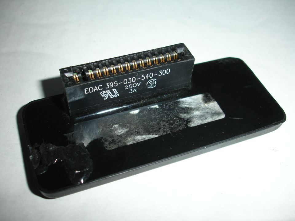 Black electronic connector with gold pins labeled EDAC 395-030-540-300, 250V, 3A, attached to a black plastic housing with adhesive residue