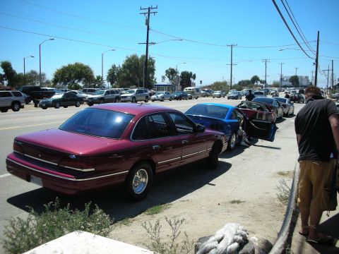 1992 Ford Crown Victoria - A maroon 1992 Ford Crown Victoria is parked in a line of vehicles on a bright, sunny day.