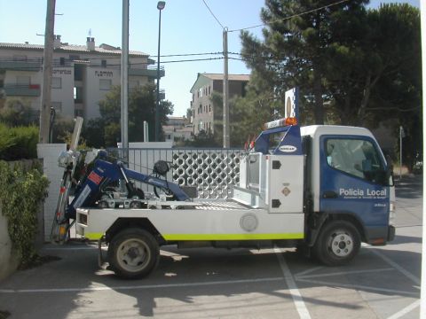 1991 Ford Crown Victoria - A tow truck with "Policia Local" markings is parked on a sunny day.
