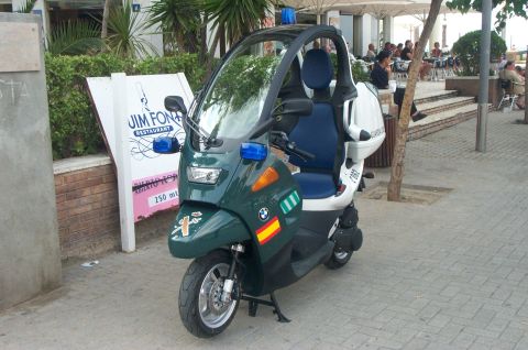 1991 Ford Crown Victoria - A three-wheeled scooter with a canopy, marked for the Guardia Civil, parked on a sidewalk.