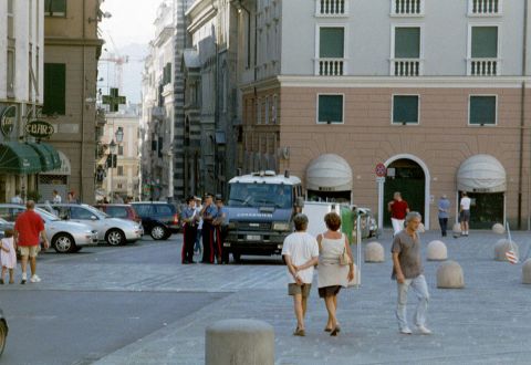1991 Ford Crown Victoria - A street scene in an Italian city features a police van and several parked cars, with pedestrians in the foreground and background.