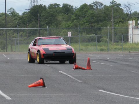 2001 Mercury Grand Marquis - A red sports car is shown on a paved lot, maneuvering around traffic cones during what appears to be a timed event.