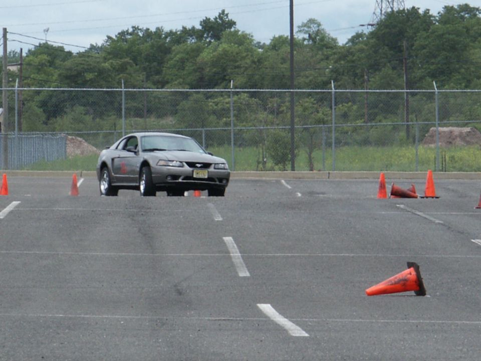 Gray Ford Mustang on a paved lot with orange cones