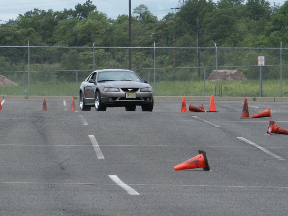 Gray Ford Mustang driving through an autocross course with orange cones