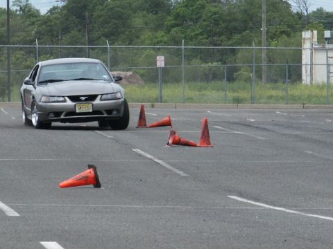 2001 Mercury Grand Marquis - Gray Ford Mustang maneuvers through an obstacle course marked by traffic cones in an asphalt lot.