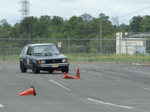 2001 Mercury Grand Marquis - A Volkswagen Golf Mk1 is shown on a paved lot with orange cones, possibly during a driving event.
