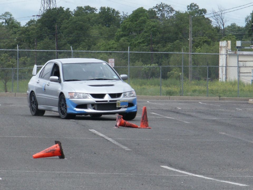 Silver Mitsubishi Lancer Evolution VIII with blue front bumper accents on a track with orange cones