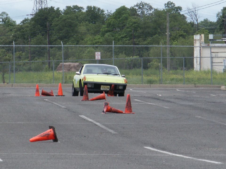 Yellow sports car driving through an autocross course with orange cones