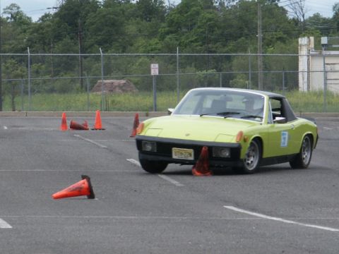 2001 Mercury Grand Marquis - A lime green sports car with a black targa top maneuvers through an autocross course marked by orange cones.