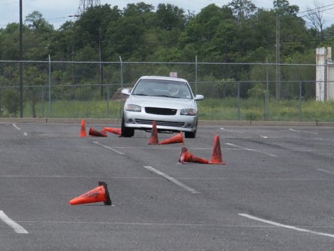 2001 Mercury Grand Marquis - A silver sedan maneuvers through an obstacle course marked by orange traffic cones in an empty parking lot.