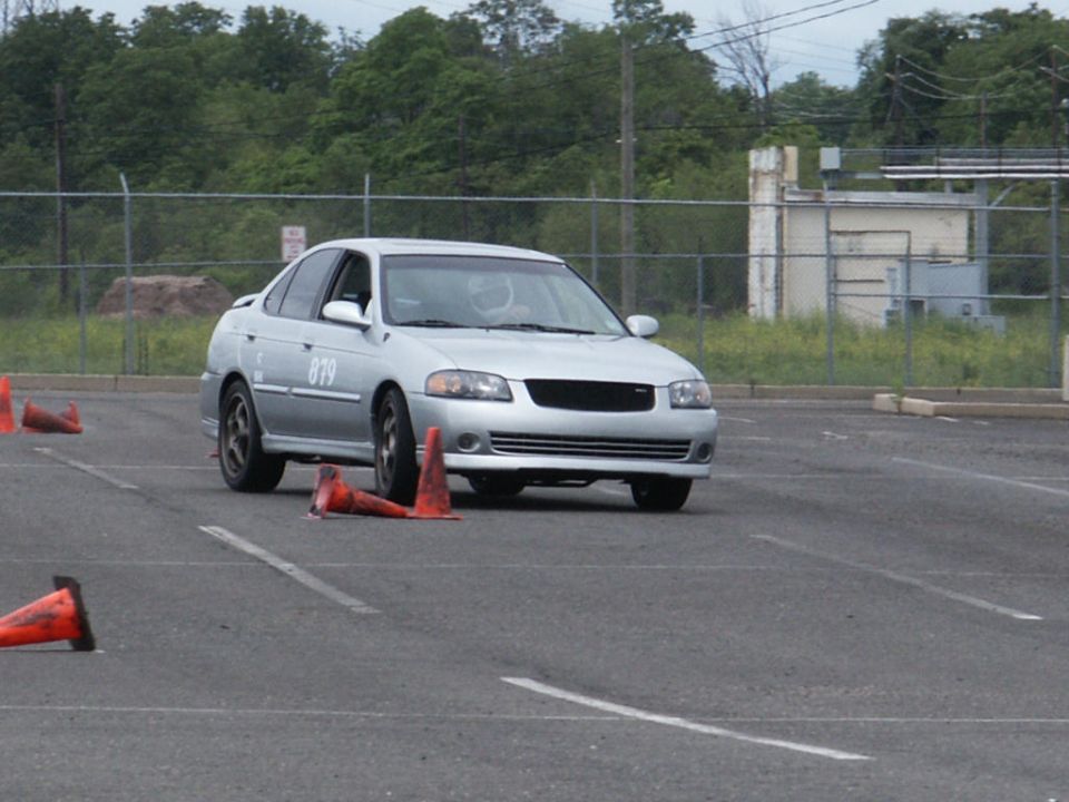 Silver sedan with number 879 on door, navigating a course marked by orange cones