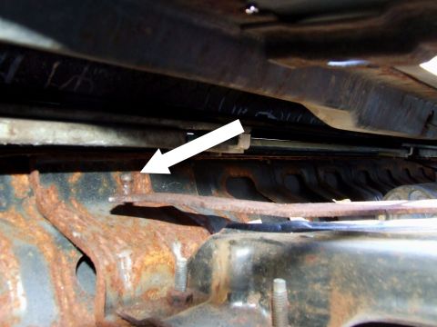 1979 Ford Bronco - Close-up of rusty metal frame, with an arrow indicating a bolt, likely related to tailgate repairs.