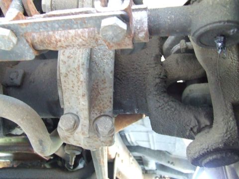 1979 Ford Bronco - This image shows a close-up view of various rusty suspension components on a vehicle, including a tie rod end and sway bar link.