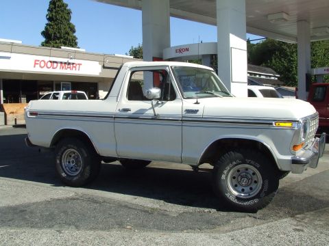 1979 Ford Bronco - A white 1979 Ford Bronco is seen from the side at a gas station with a Food Mart in the background.